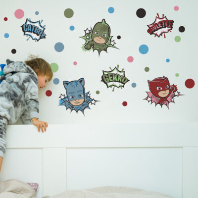 comic PJ Masks wall sticker pack shown on a white wall behind a white bed