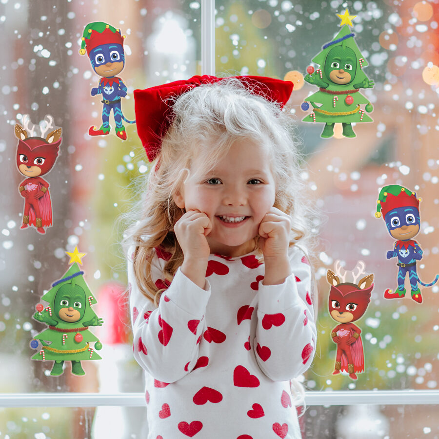 Christmas PJ Masks window stickers shown on a window behind a young girl