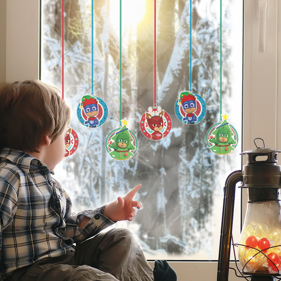 PJ Masks christmas baubles window stickers shown on a snowy window behind a child
