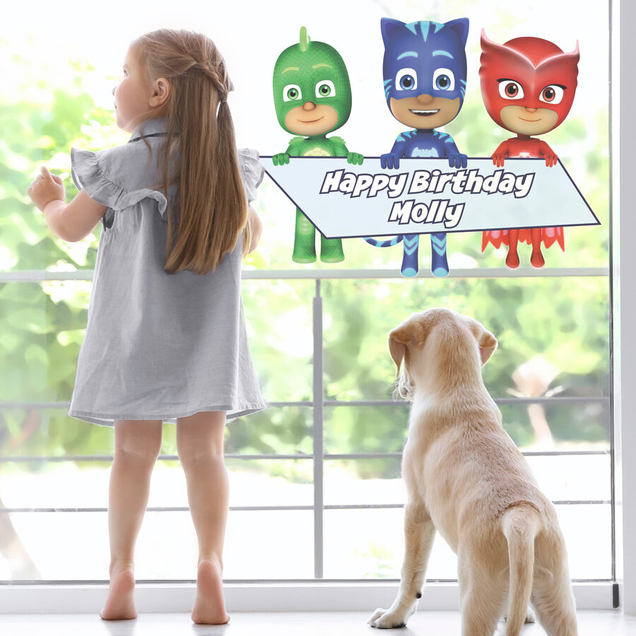 PJ Masks birthday window sticker in large shown on a window behind a girl and her dog