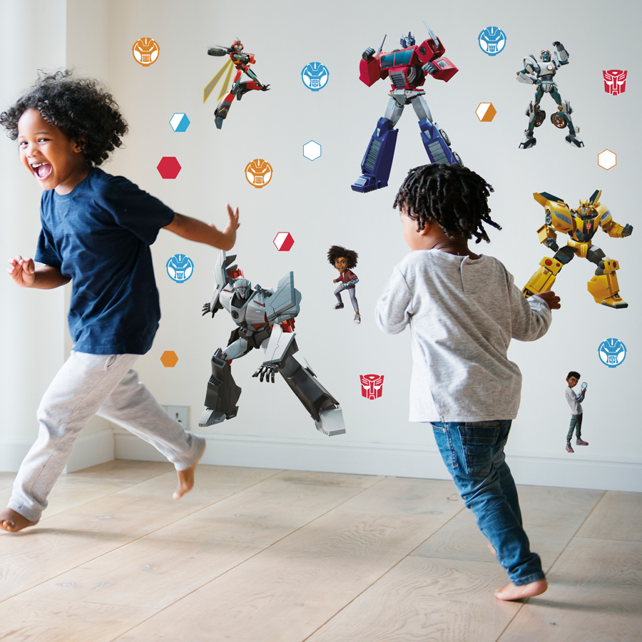 Transformers Earthspark wall sticker pack large shown on a white wall behind two children running
