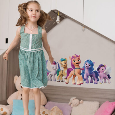 My Little Pony group wall sticker option 1 large shown on a cream wall above a wooden bed behind a child jumping