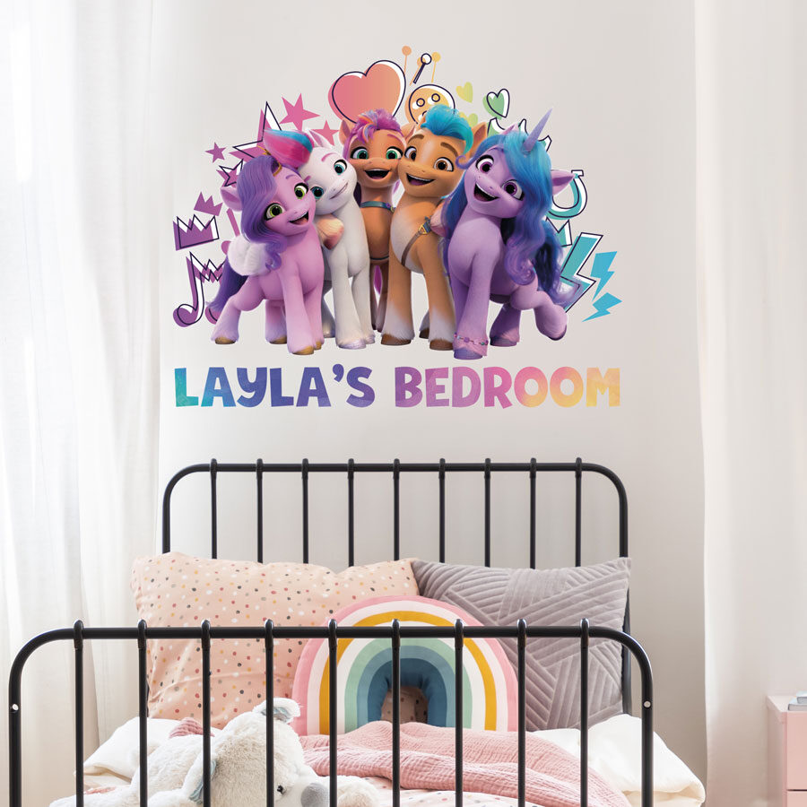 Personalised My Little Pony wall sticker shown on a white wall behind a black bed frame with pink, white and grey bedding