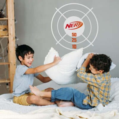 Nerf target wall sticker option 2 shown on a grey wall behind two children having a pillow fight