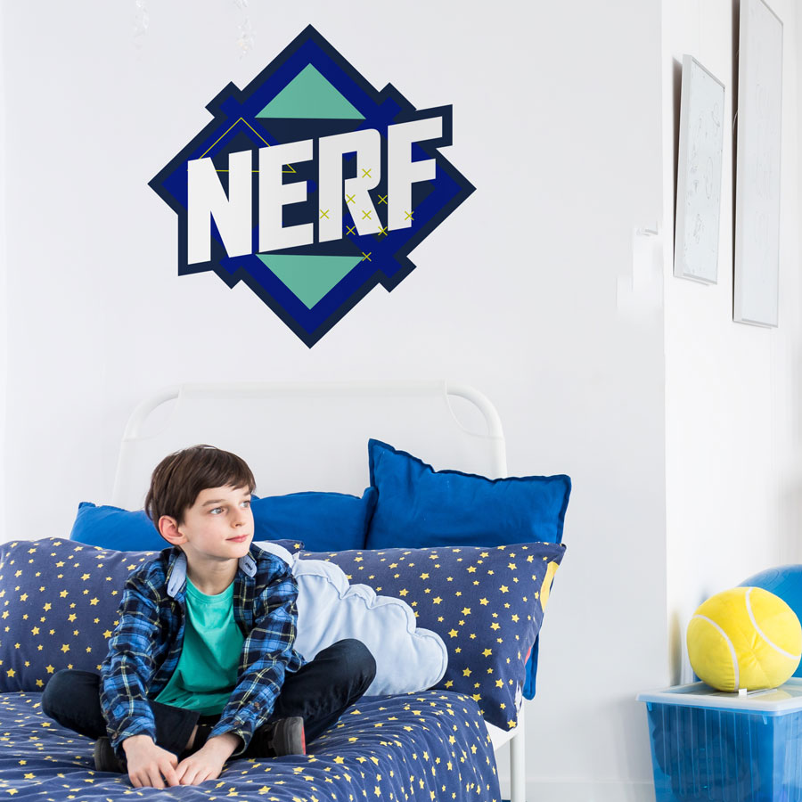 Blue Nerf logo wall sticker extra large shown on a white wall behind a child sat on blue bed