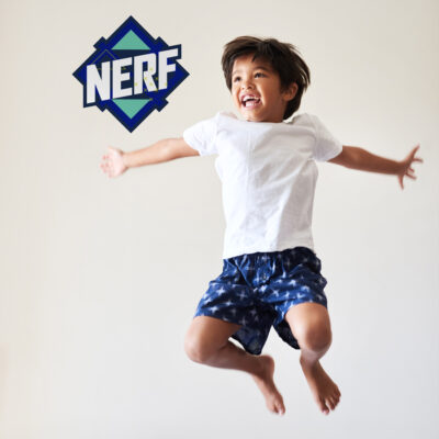 Blue Nerf logo wall sticker regular shown on a white wall behind a child jumping