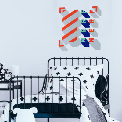 3D Nerf wall sticker large shown on a light grey wall behind a black and white bed