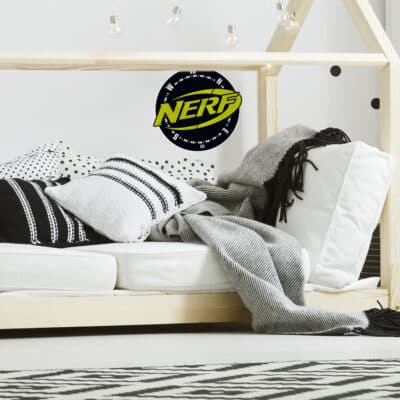 Nerf compass wall sticker regular shown on a white wall behind a light wood bed with white, black and grey bedding
