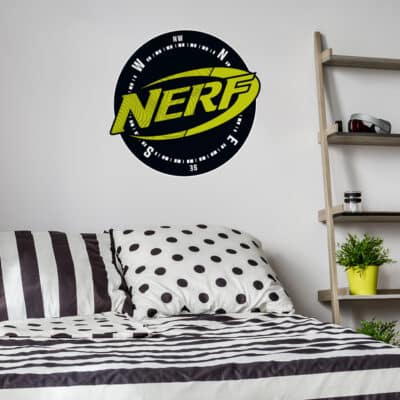 Nerf compass wall sticker extra large on a white wall behind a black and white bed spread and black shelving unit