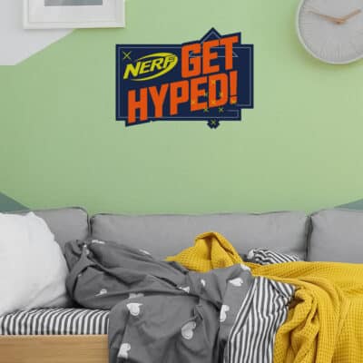 Get Hyped! Nerf wall sticker regular shown on a green wall behind a grey sofa bed with yellow blanket