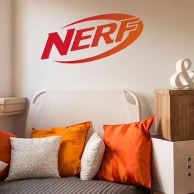Nerf wall sticker shown on a light beige bed behind a light cream sofa with orange and white pillows