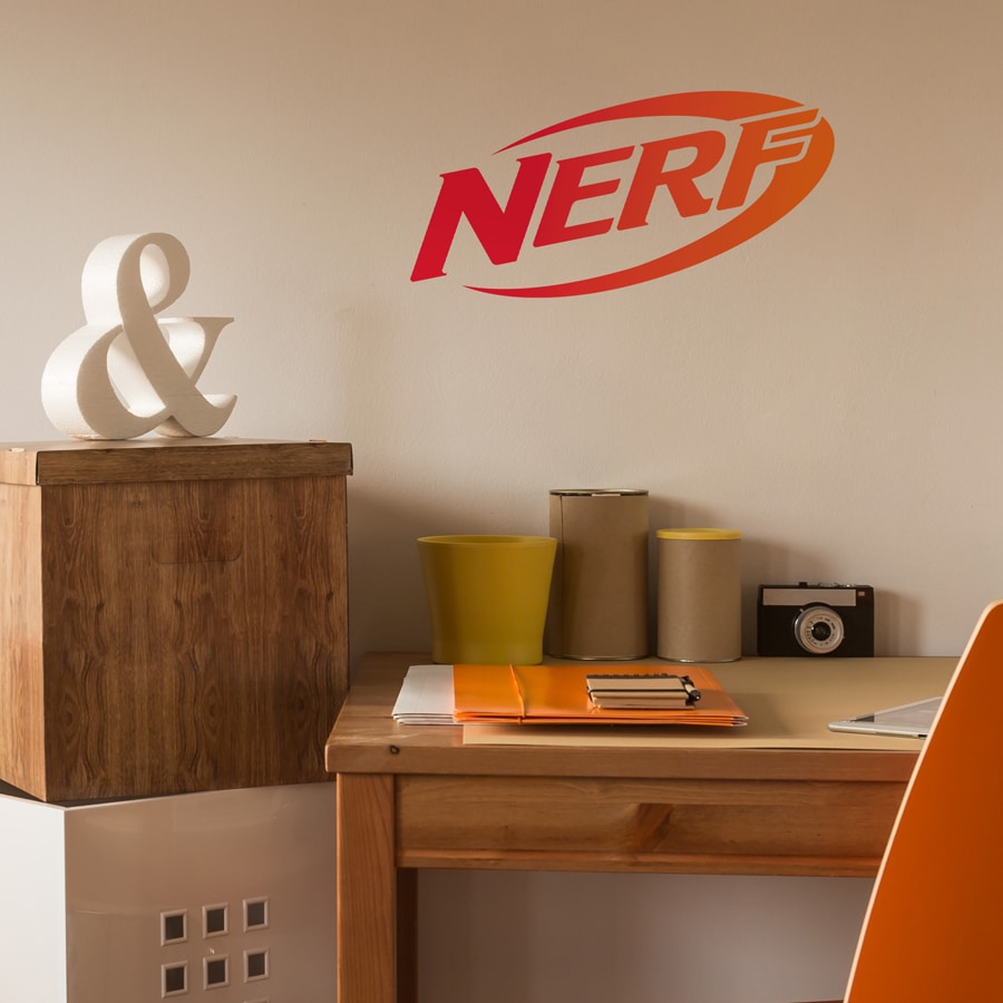 Nerf wall sticker regular shown on a beige wall behind a wood desk with orange and yellow stationery
