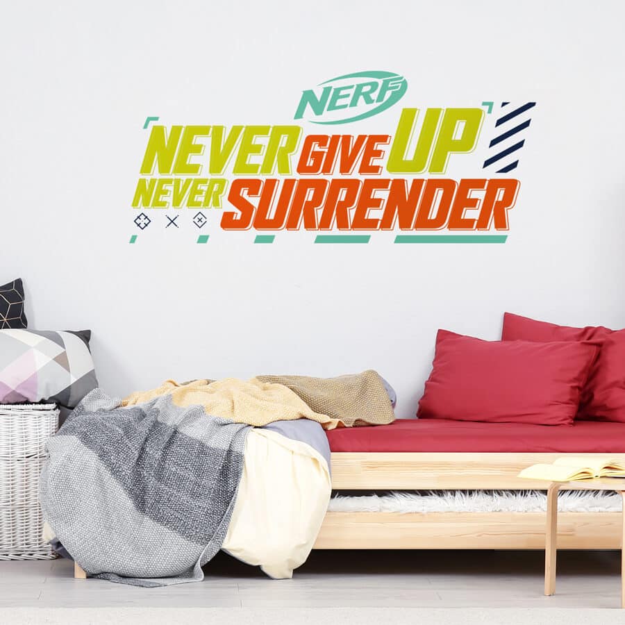Never Give Up wall sticker shown on a white wall behind a wooden sofa bed with red and grey bedding