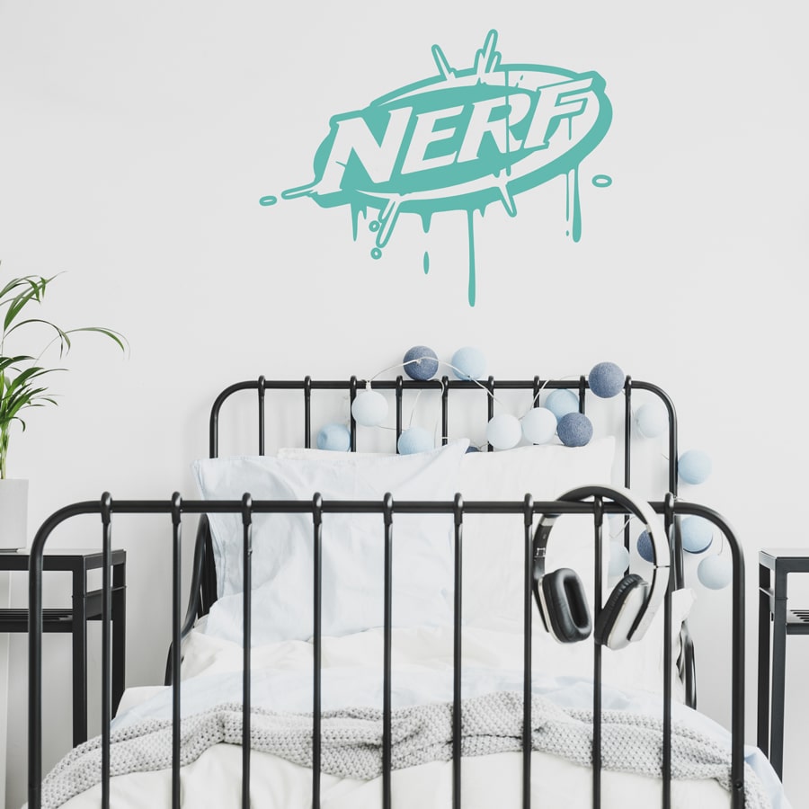 Nerf splat wall sticker shown on a white wall behind a black bed wit white bedding
