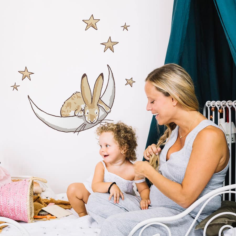Moon & stars wall sticker on a white wall behind a mother and child on a white bed