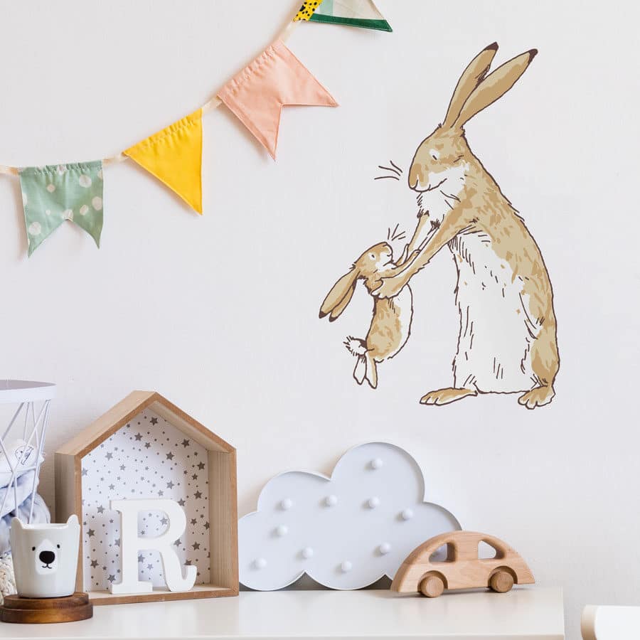 Nutbrown Hares wall sticker regular shown on a white wall under some pastel coloured bunting above a chest of drawers with wooden toys on top