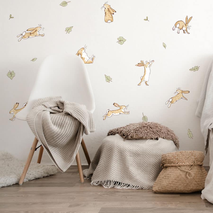 Hares & leaves wall sticker pack shown on a white wall behind a white chair with beige blankets