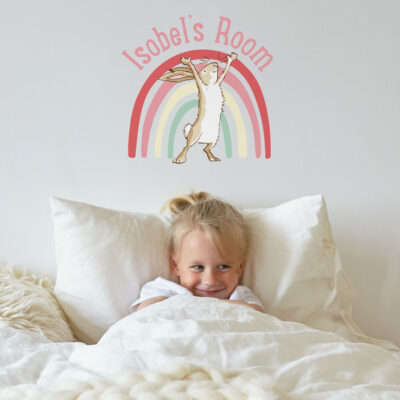 Personalised rainbow hare wall sticker regular pink on a white wall behind a child in a white bed