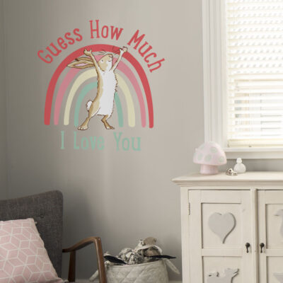 Rainbow hare wall sticker with text large on a light grey wall behind a grey chair and white dresser