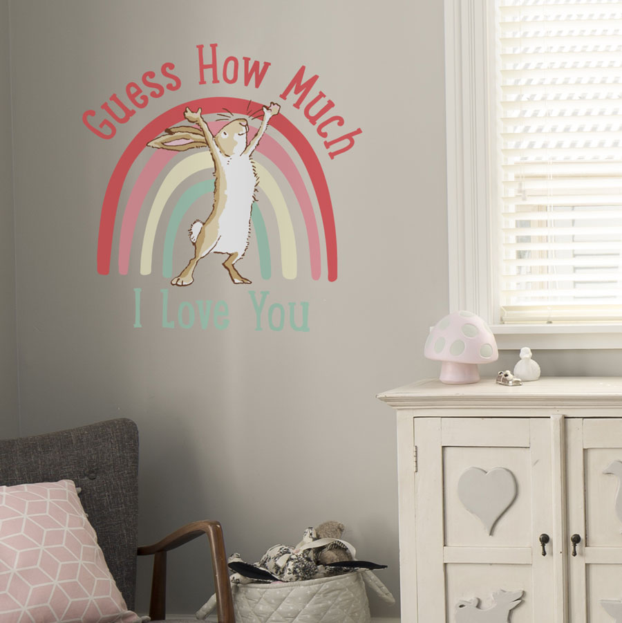 Rainbow hare wall sticker with text large on a light grey wall behind a grey chair and white dresser