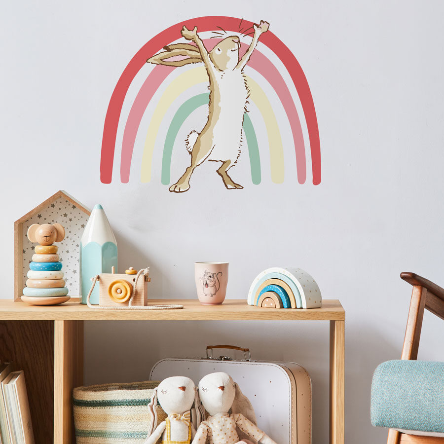 Rainbow hare wall sticker with no text on a white wall behind a wooden book shelf with colourful wooden toys