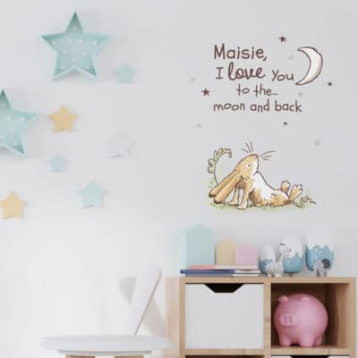 Personalised hare wall sticker shown on a light grey wall behind a wooden cabinet and next to blue star decorations
