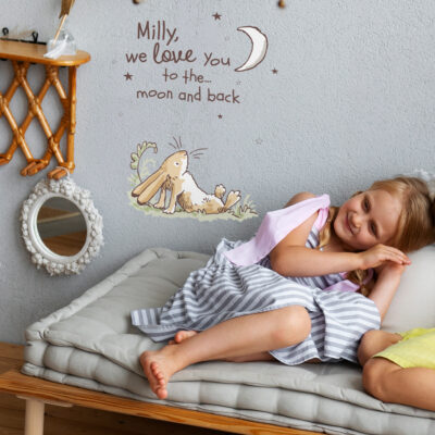 Personalised hare wall sticker shown on a grey wall behind a child sat on a grey bed