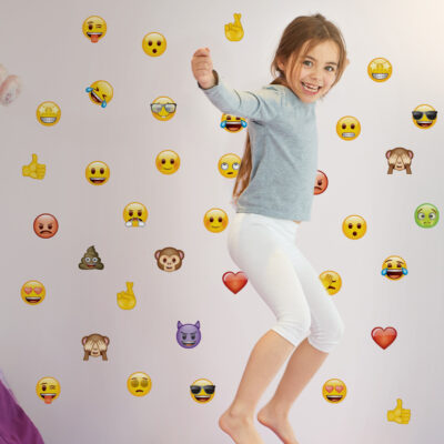 Mixed emoji wall sticker pack large shown on a white wall behind a child jumping on a bed