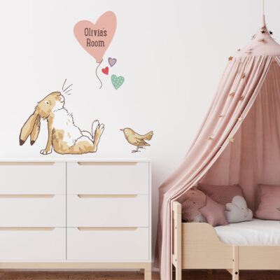 Personalised hare & balloon wall sticker regular shown on a white wall above a white chest of drawers next to a pink bed