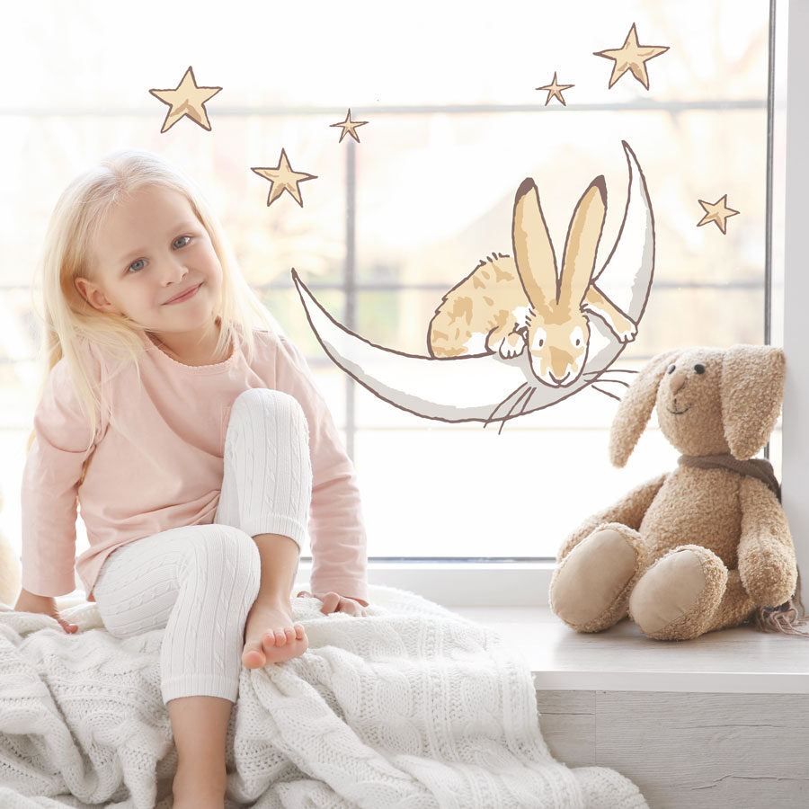 Moon & stars window stickers large shown on a window behind a young child with a teddy rabbit