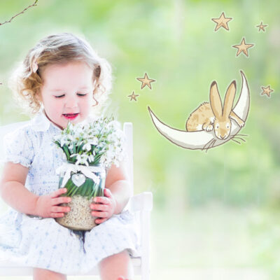 Moon & stars window stickers regular shown on a window behind a young child holding a plant pot with white flowers
