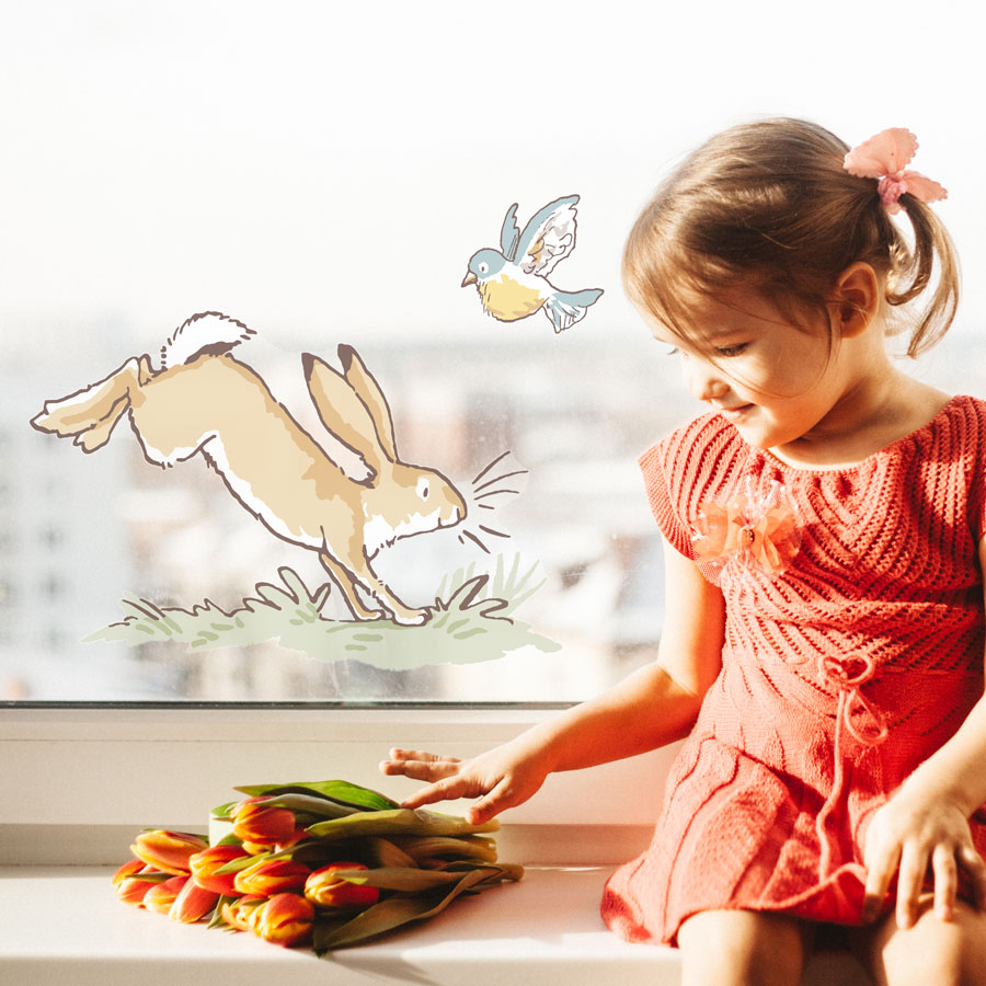 Hopping hare window sticker regular shown on a window behind a young child with some tulips