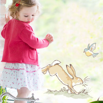Hopping hare window sticker large on a window behind a toddler kneeling infront