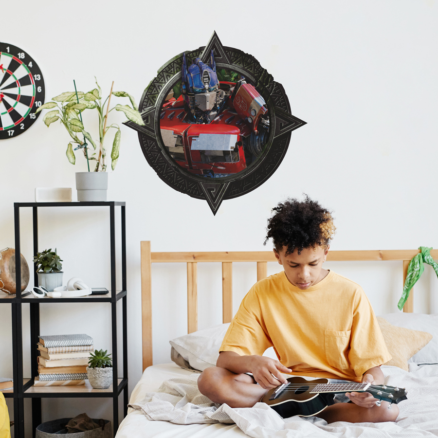 Optimus Prime wall sticker shown on a white wall above a bed with child playing instrument.
