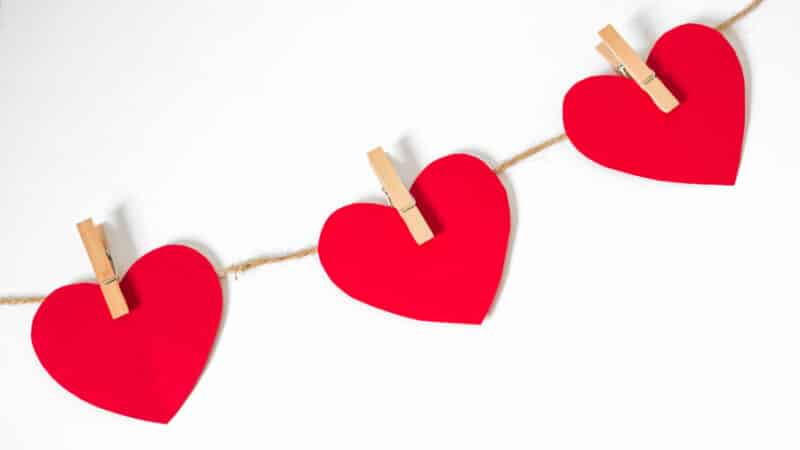 Red hearts with string and pegs on a white background