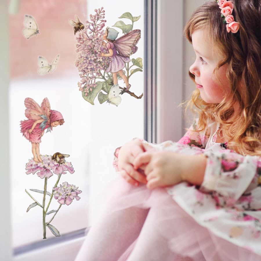 Pink Flower Fairies Window Stickers on a window in front of girl
