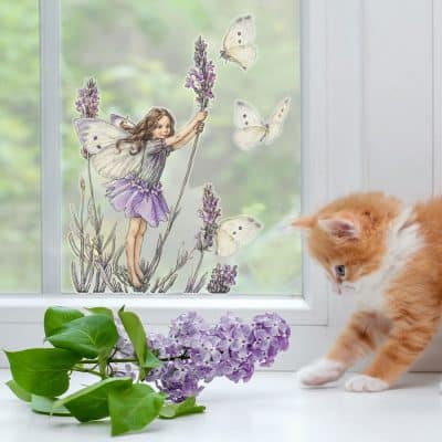 The Lavender Fairy Window Sticker on a window with cat and flowers