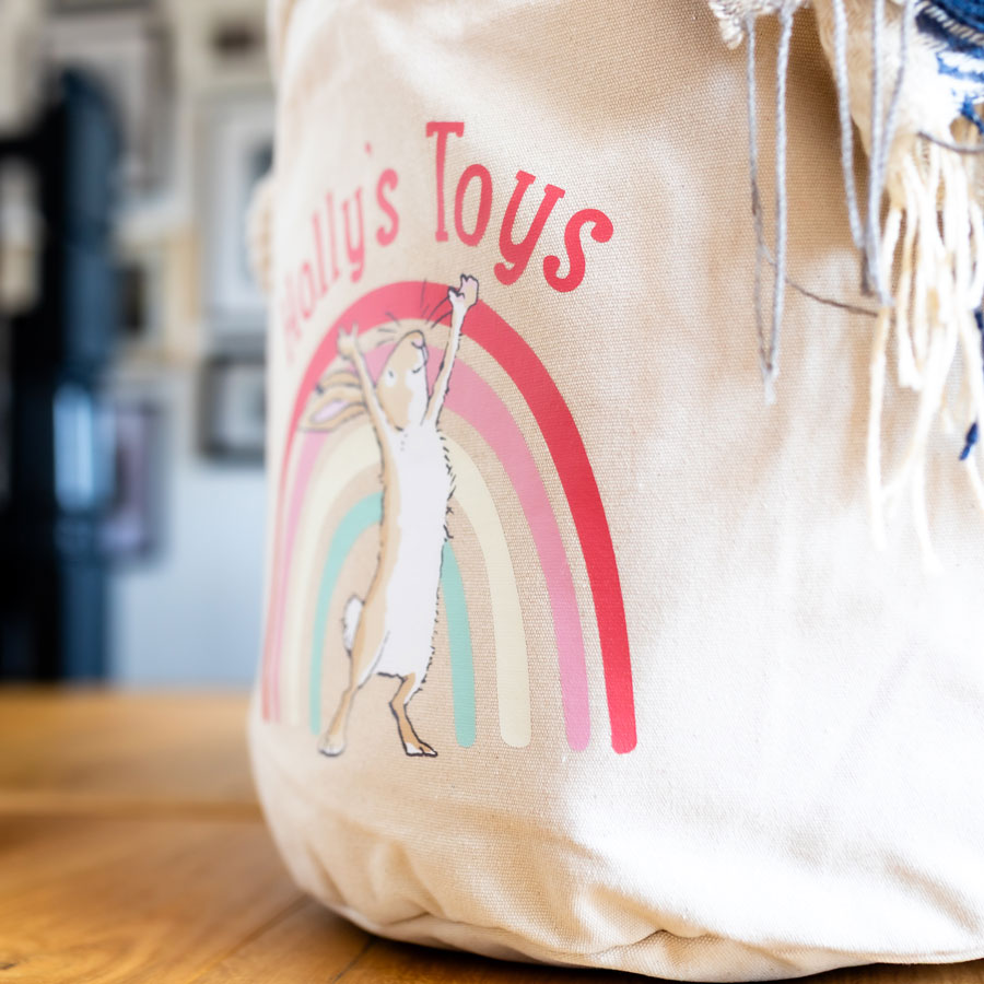 Side view of a personalised Guess How Much I Love You storage basket showing Little Nutbrown Hare and rainbow detail, designed for nursery storage.