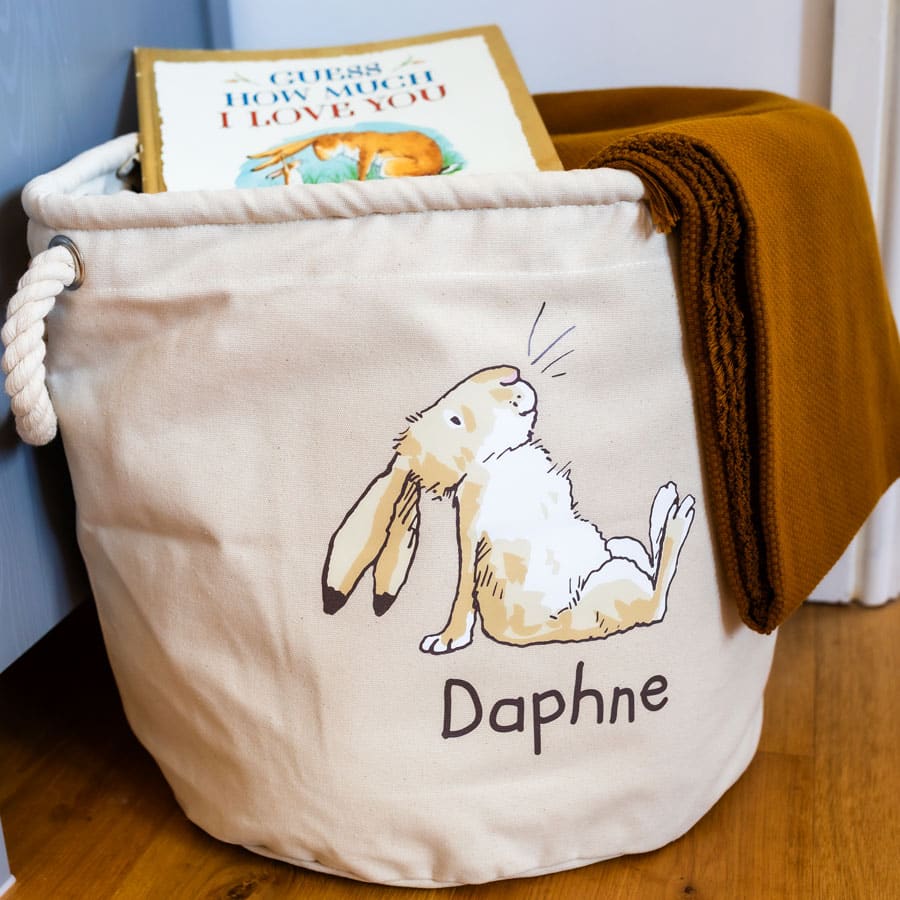 Guess How Much I Love You soft storage basket with Little Nutbrown Hare design, styled in a nursery with a doll, book and blanket inside.