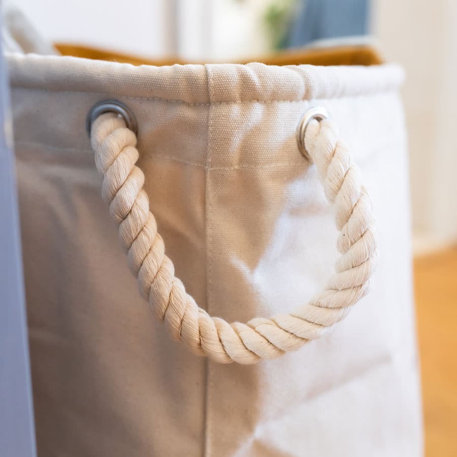 Detail of thick rope handle on a soft storage basket – made from natural cotton canvas for practical nursery storage.