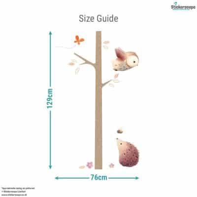 Size guide for woodland tree wall sticker showing total design height of 129cm and width of 76cm with owl, hedgehog and leaves.