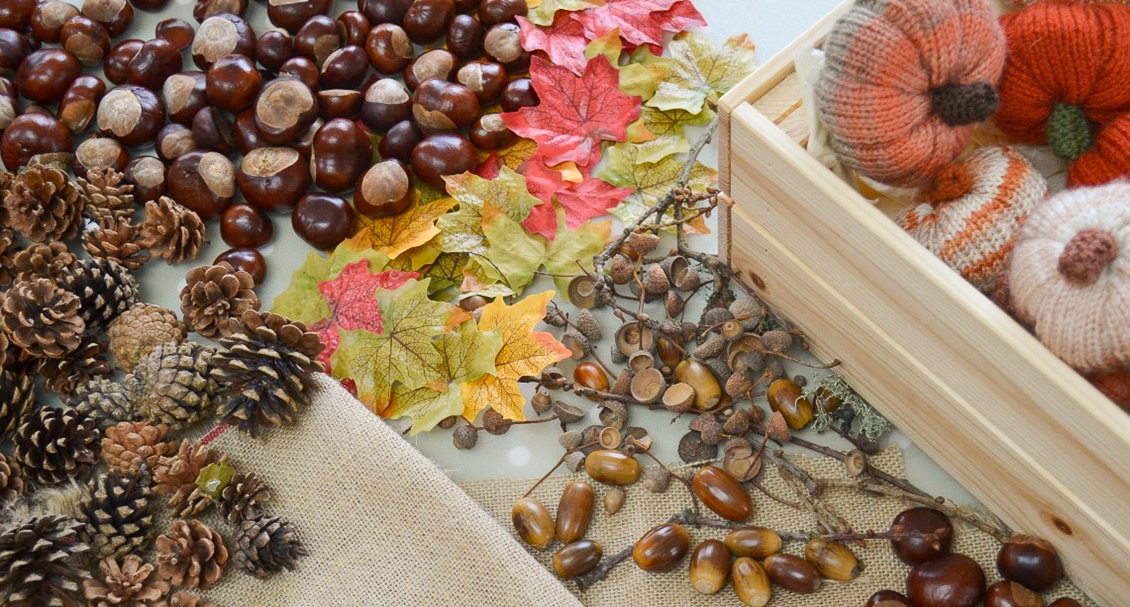 Decorating an Autumn wreath for October using pine cones, conkers and leaves